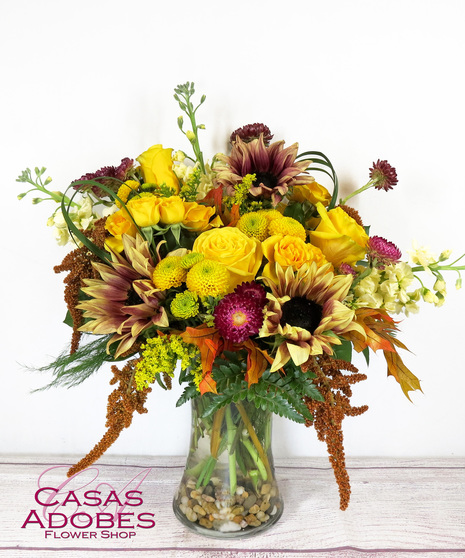 Vase with fall sunflowers, roses, yellow stock, amaranthus, strawflower, solid aster, fall leaves and bear grass loops