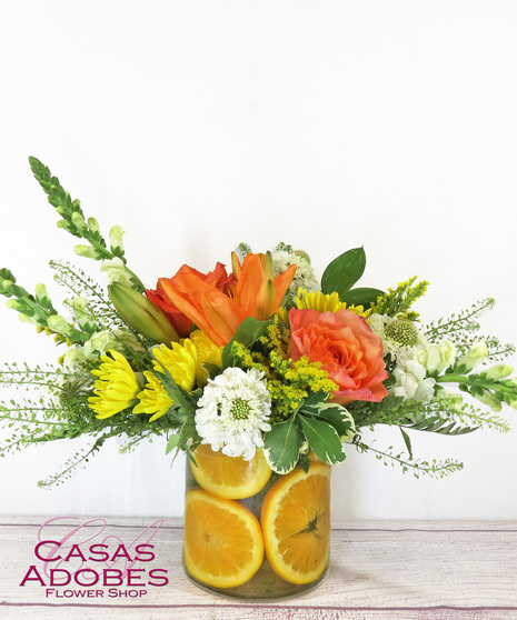 Cylinder vase with summer flowers and fresh citrus cut up lining the inside of the vase