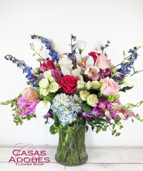 Vase with hot pink roses, light pink roses, lisianthus, purple dendrobium orchids, blue hydrangea and blue delphinium 