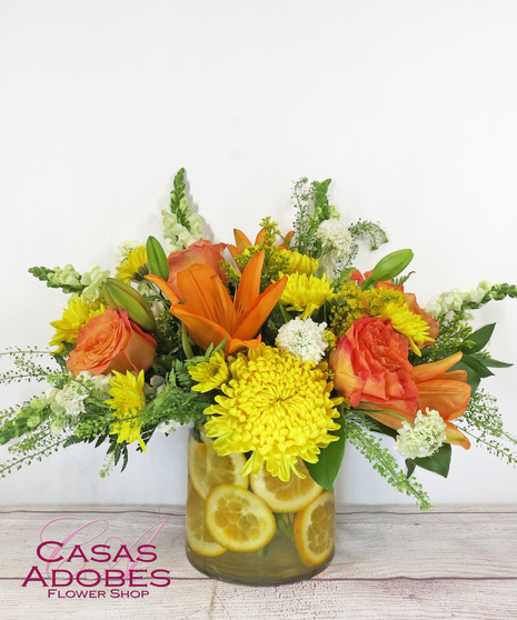 Cylinder vase with summer flowers and fresh citrus cut up lining the inside of the vase