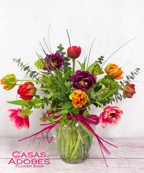 Dozen colorful tulips in a vase with accent greenery and filler